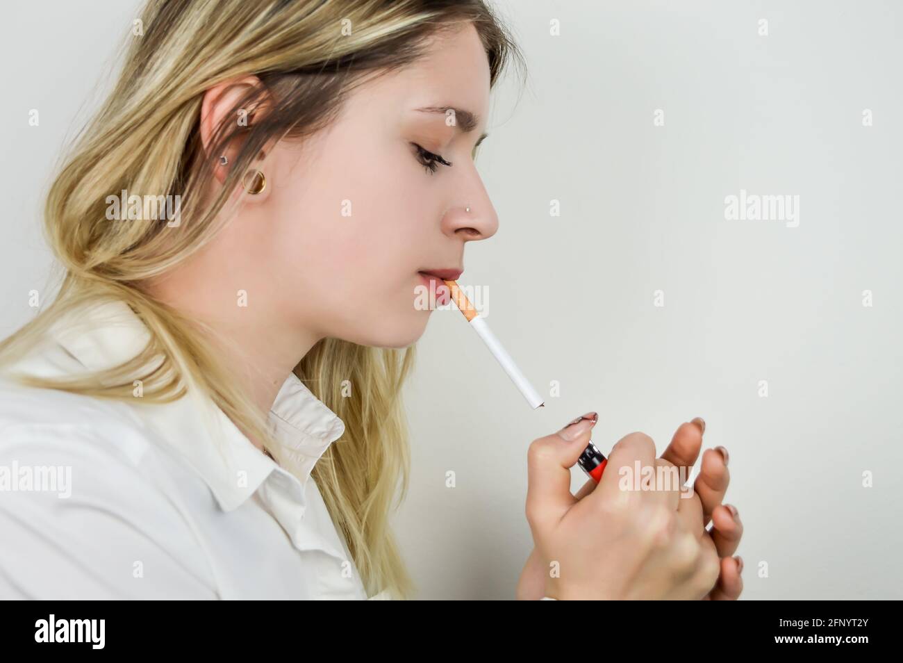 Porträt einer schönen jungen blonden Frau, die sich vorbereitet Um eine Zigarette anzuzünden Stockfoto