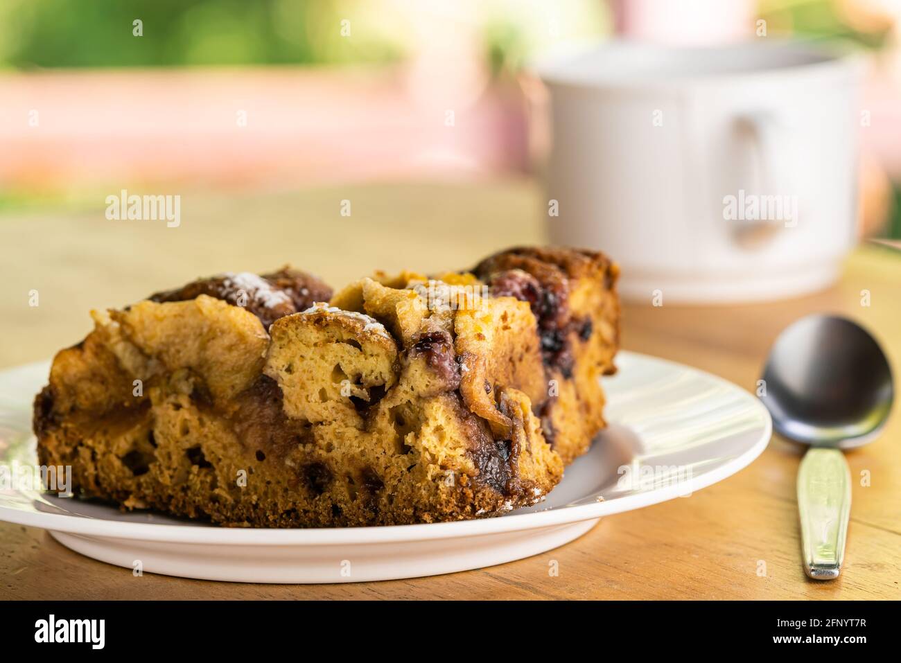 Seitenansicht Stück Apfelkuchen in einer weißen Schale und eine Tasse Kaffee, Metalllöffel auf Holztisch. Stockfoto