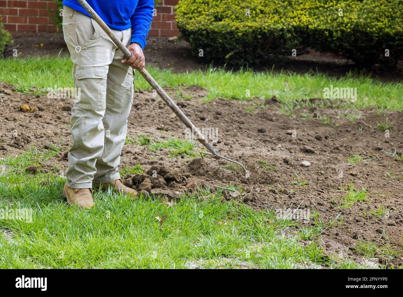 Stadtdienstmitarbeiter Gärtner mit einem Metallrechen am Aktive Arbeit beenden Stockfoto