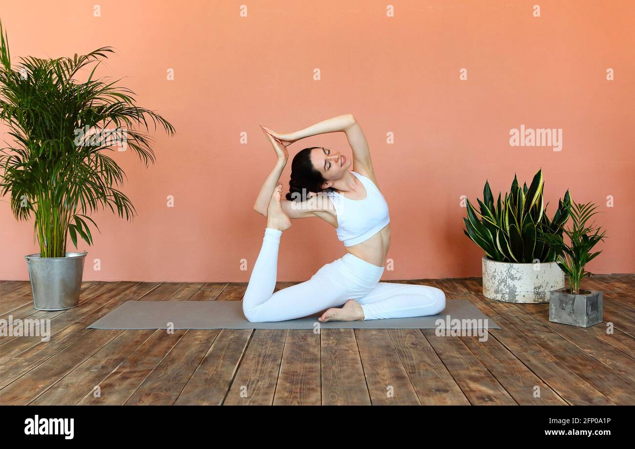 Junge Brünette weiblich in weißen Sportswear auf Matte und tun Yoga, während Achtsamkeit üben Stockfoto