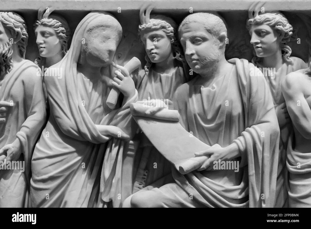 Schwarz-Weiß-Foto von alten römischen Skulpturen geschnitzt auf Marmorwand, die eine Frau mit einem Schleier zeigt, der mit einem spricht Mann, während er von Männern mit Hörnern umgeben ist Stockfoto