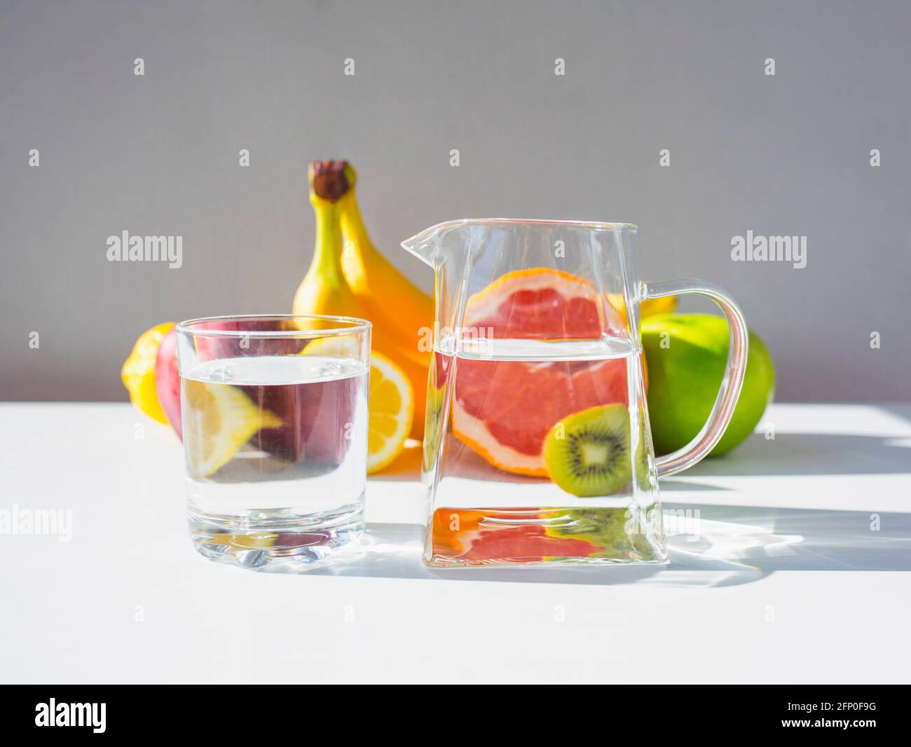 Kanne und Glas mit reinem Wasser und frischem Obst. Stockfoto