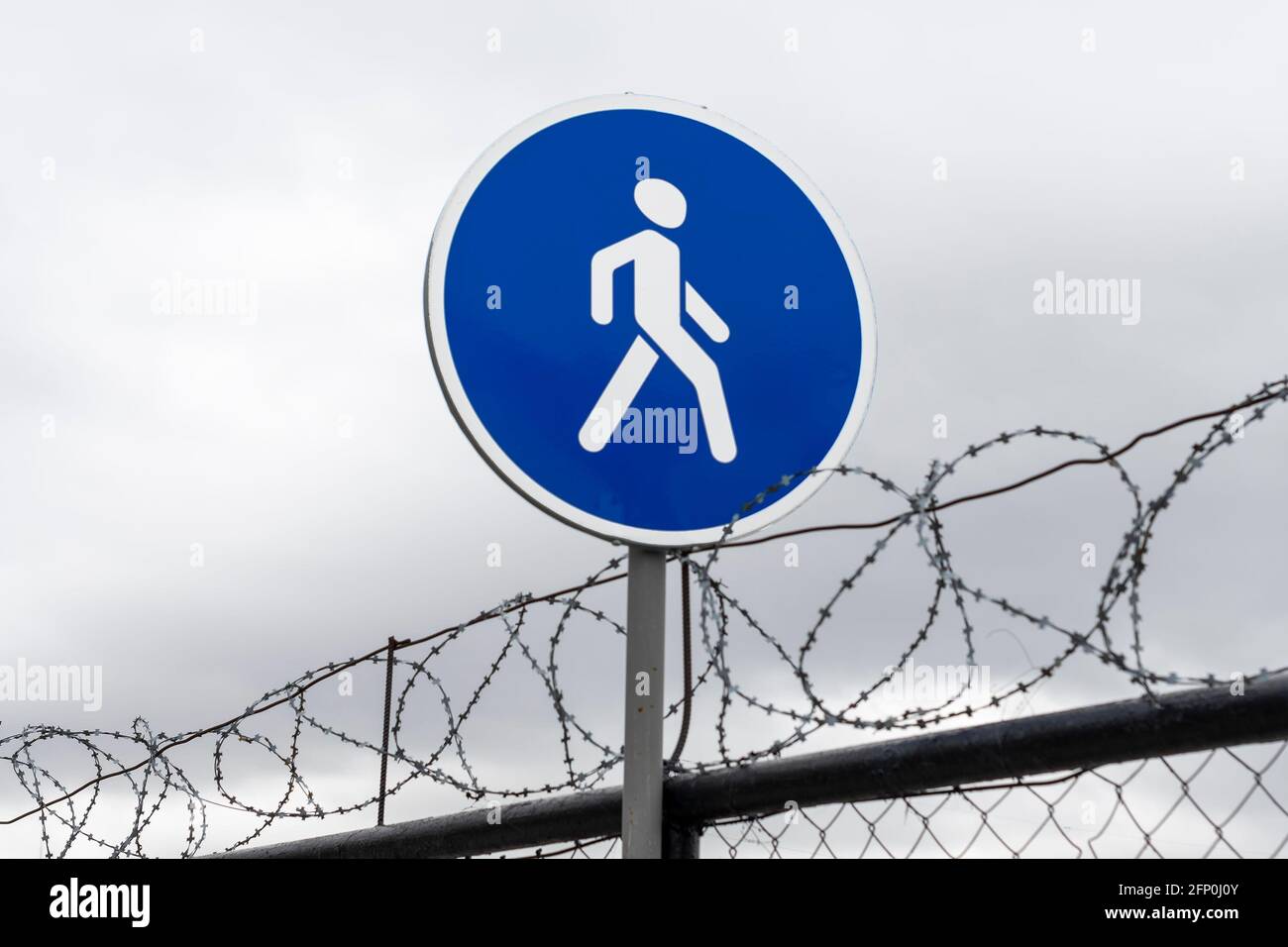 Straßenschild Gehweg und Stacheldrahtzaun. Konzept. Stockfoto