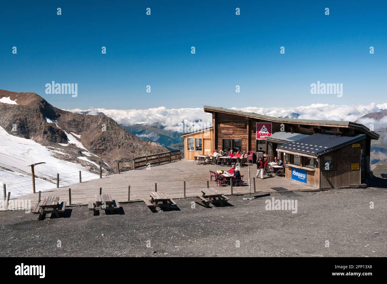 Menschen entspannen sich im Café, das sich oben an der Seilbahn La Meije (3200 m) mit Blick auf den Girose-Gletscher in der Nähe der Stadt La Grave, Ecrins Nationa, befindet Stockfoto