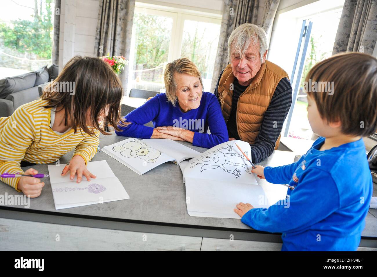 Ein Rentnerpaar verbringt Zeit mit ihren Enkeln auf einem Urlaub in Cornwall, Großbritannien. Unterhaltsam die Enkel Zeichnung und Malbilder. Stockfoto