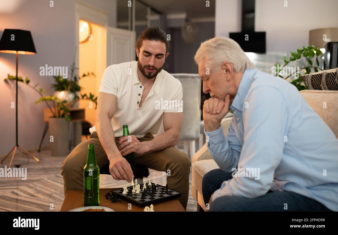 Ältere und junge Männer mit Bier spielen Schach Stockfoto