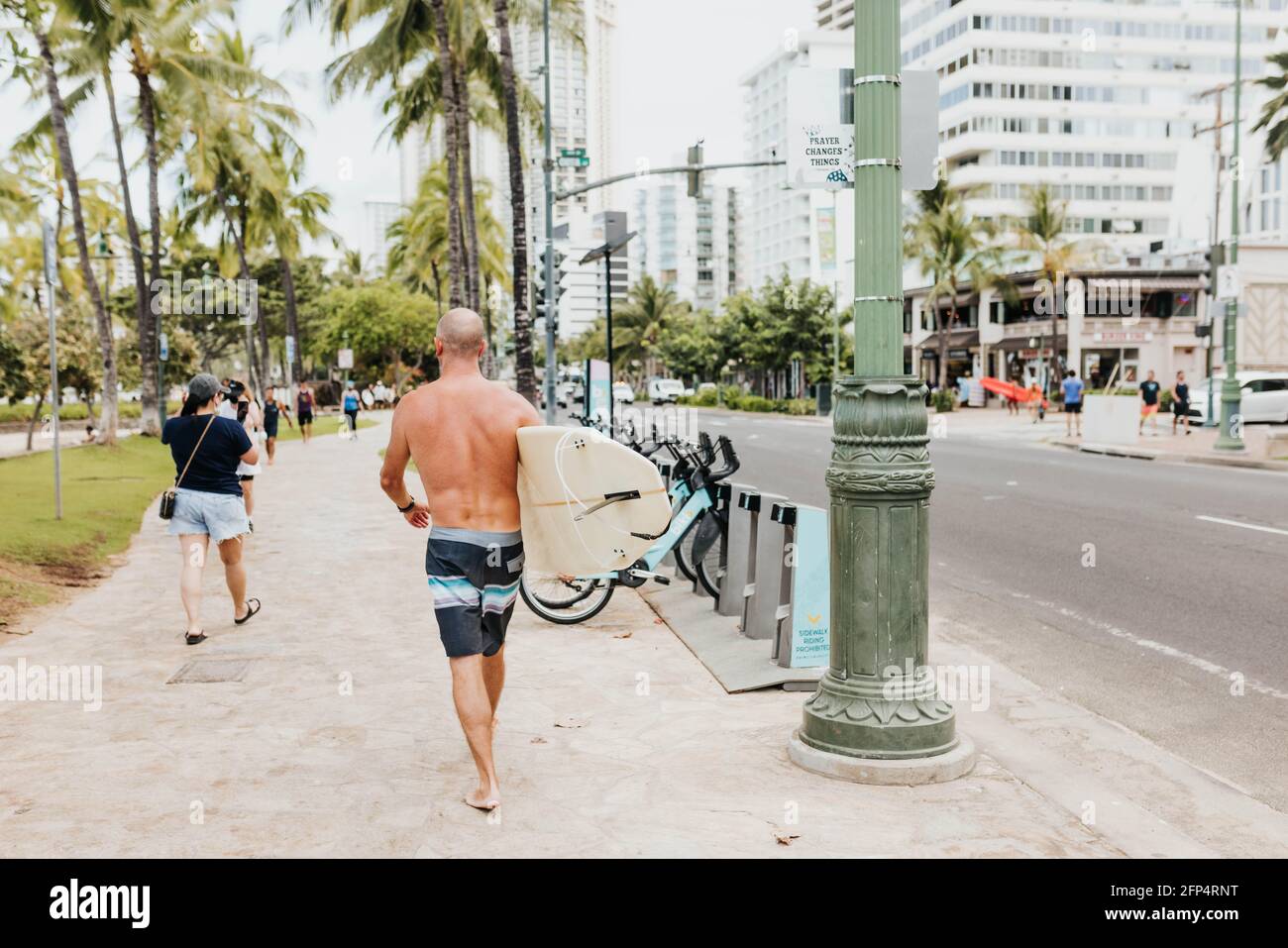 Mann läuft mit Surfbrett zum Strand in Waikiki Stockfoto