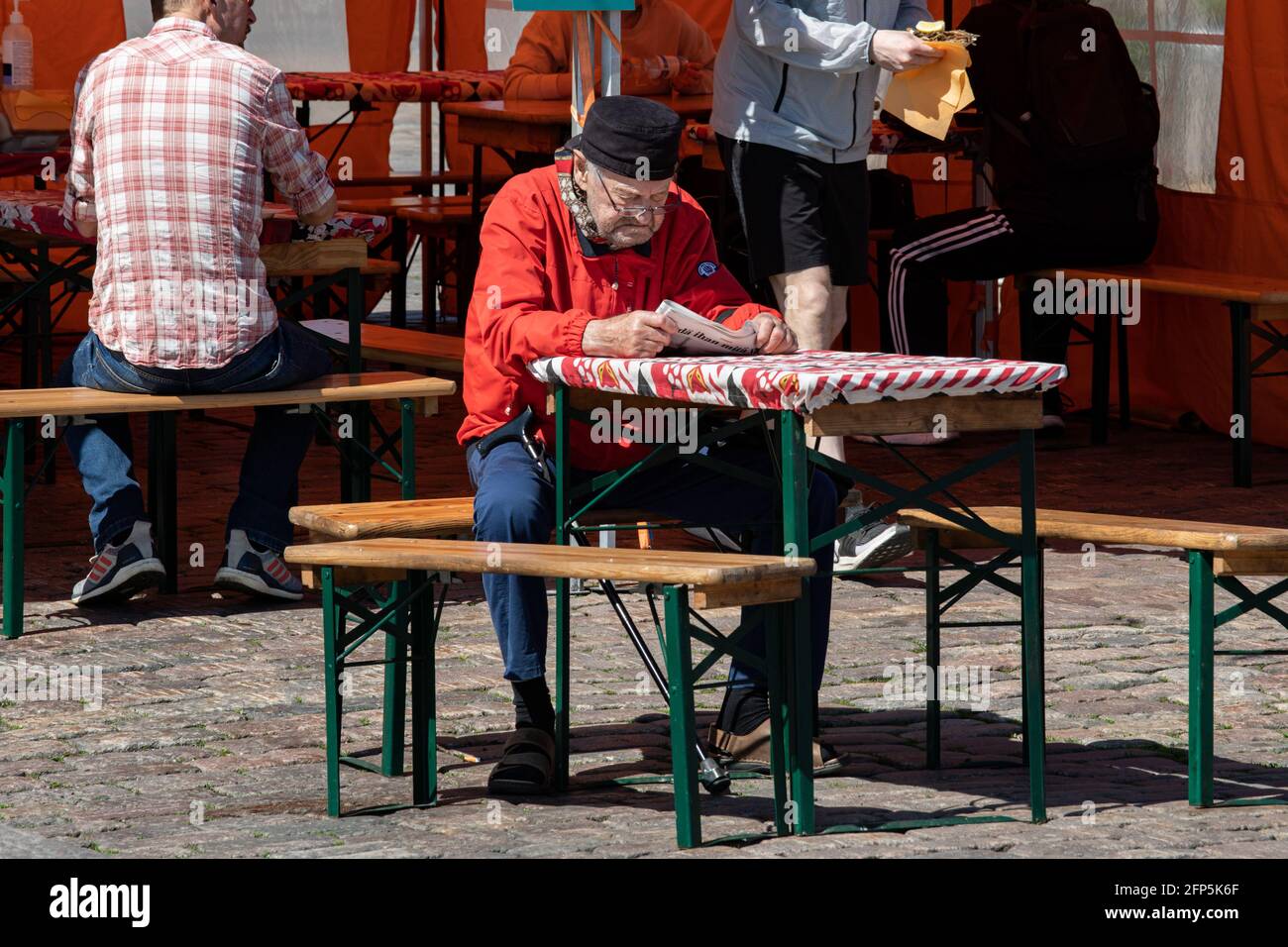 Ältere Bürger lesen Zeitung am Café-Tisch im Freien auf dem Marktplatz in Helsinki, Finnland Stockfoto