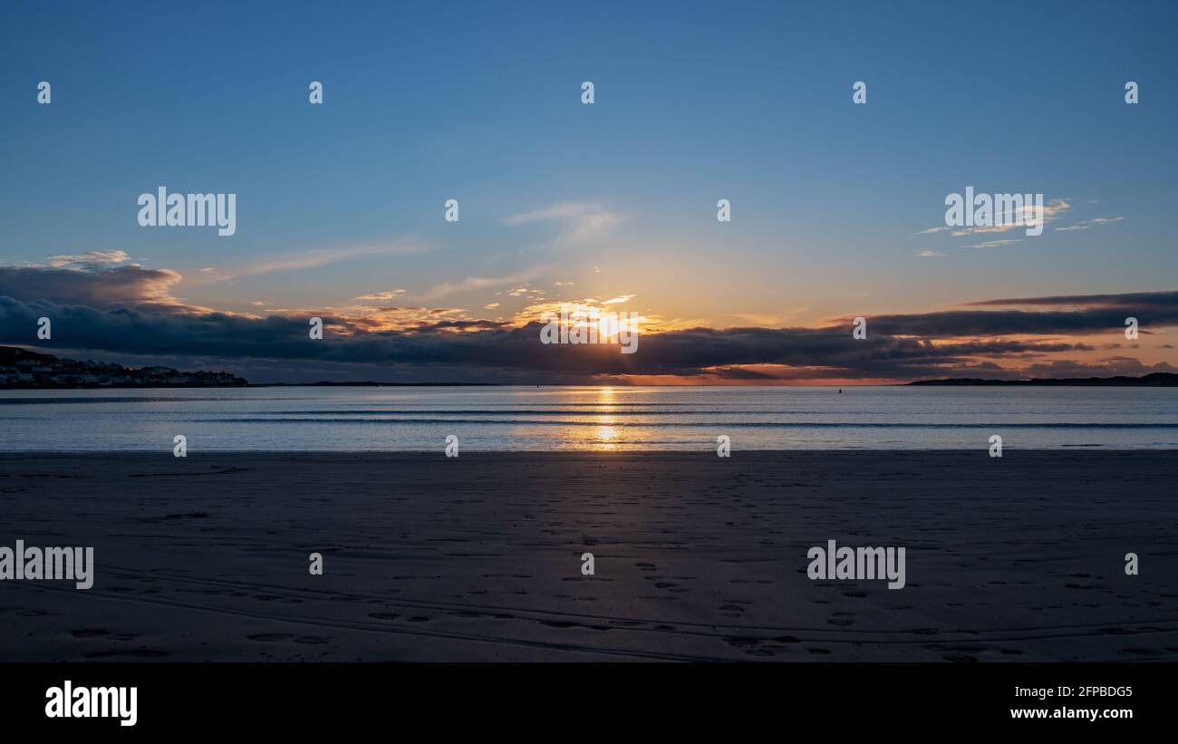 Ziemlich allgemeiner, leerer Sandstrand mit Panoramablick, Meer und Hintergrund bei Sonnenuntergang. Stockfoto
