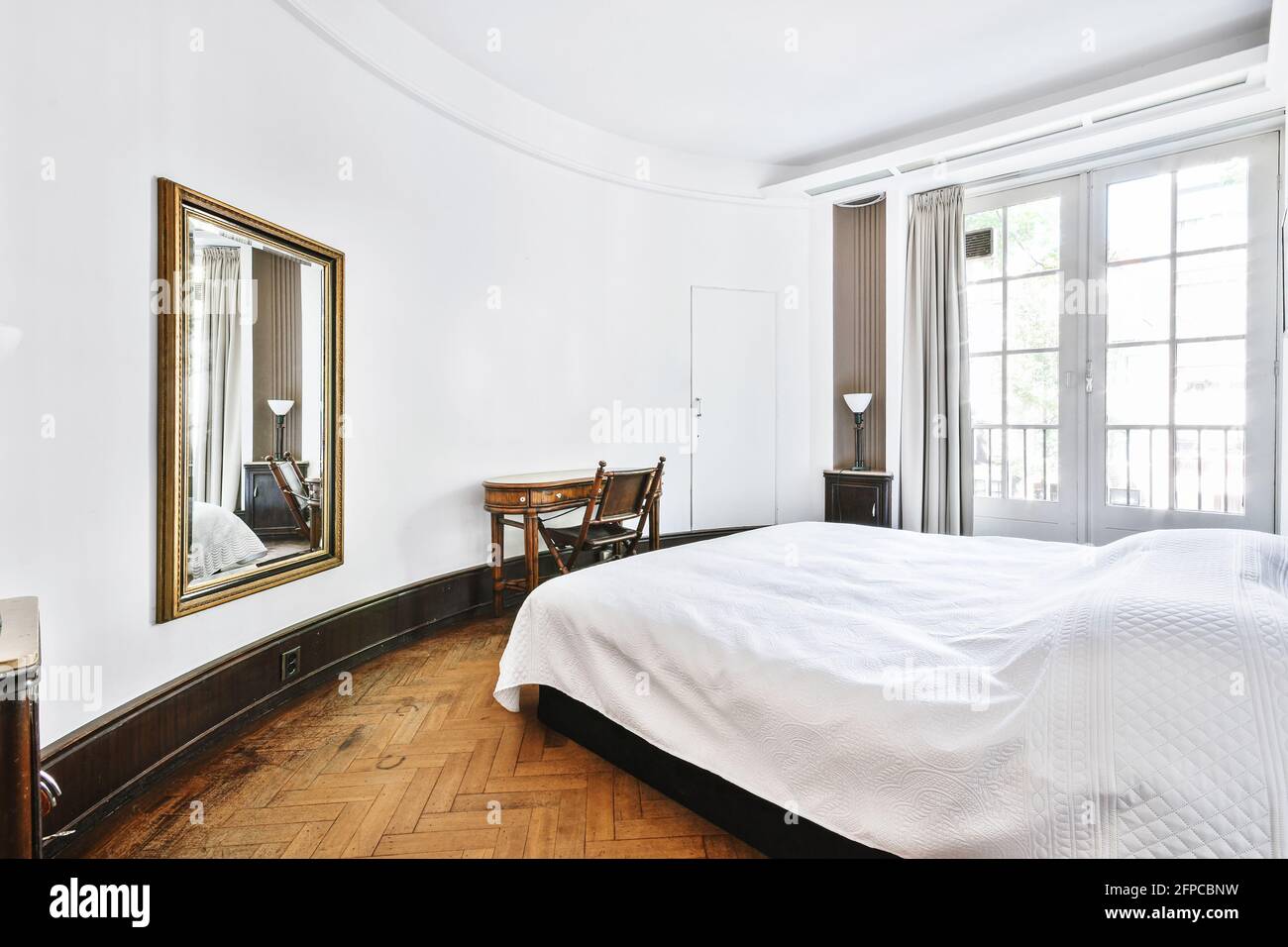 Stilvolles Wohndesign des Schlafzimmers mit ungewöhnlicher geschwungener  Architektur Weiße Wände mit Bett und Vintage-Holztisch Mit Stuhl  Stockfotografie - Alamy
