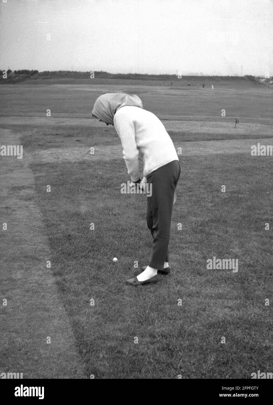 1962, historisch, eine Dame in einem Kopftuch, die Golf auf einem Putting Green am Meer oder einem Putting Course in Littlehampton, West Sussex, England, Großbritannien, spielt. Stockfoto