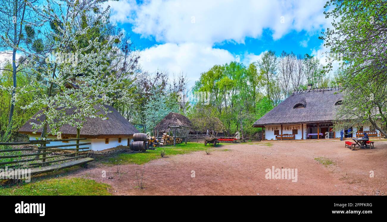 Panorama des Hofes an der Shynok (traditionelles ukrainisches Restaurant und Bar) mit Hata-Häusern, Tischen und Bänken, Fässern und einer Scheune im Hintergrund, Ma Stockfoto