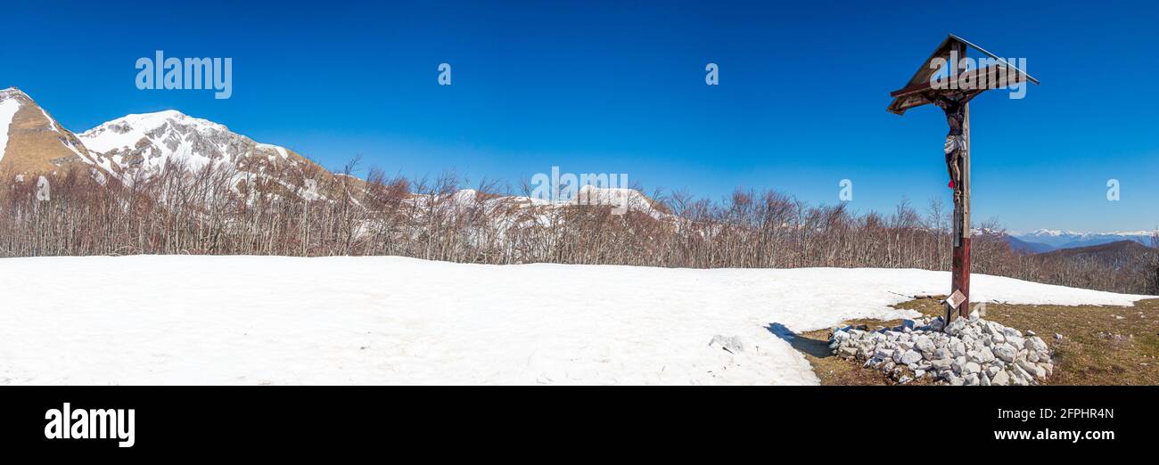 Panorama-Landschaftsansicht des christlichen Kreuzes auf dem Bergrücken, kein Mensch Tag blau klaren Himmel Winterschnee, Spiritualität Konzept Stockfoto