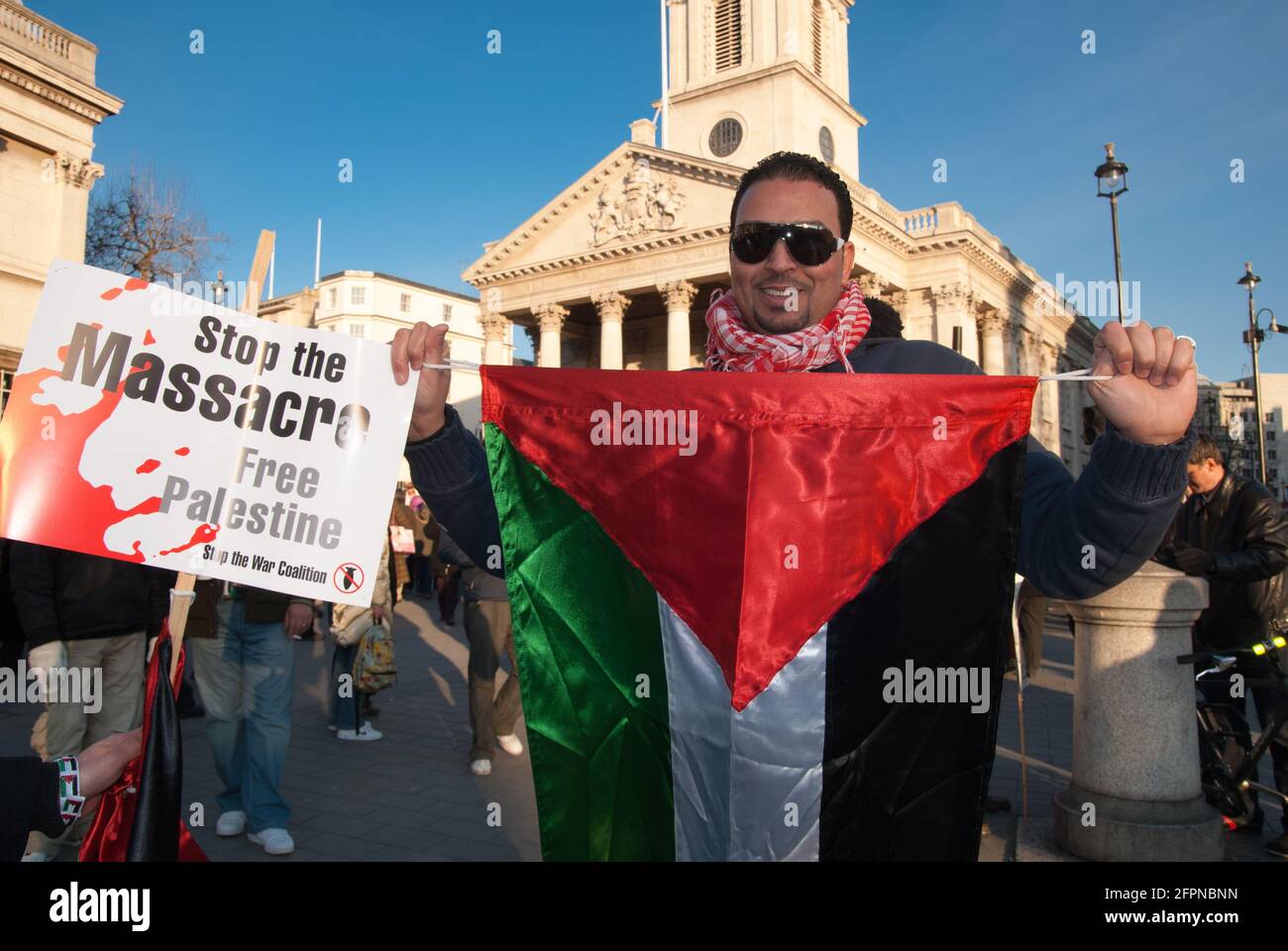 TRAFALGAR SQUARE, LONDON - 9. JANUAR 2009: Freedom for Palestine Demo, ein Mann in dunkler Brille steht und hält eine palästinensische Fahne vor sich Stockfoto