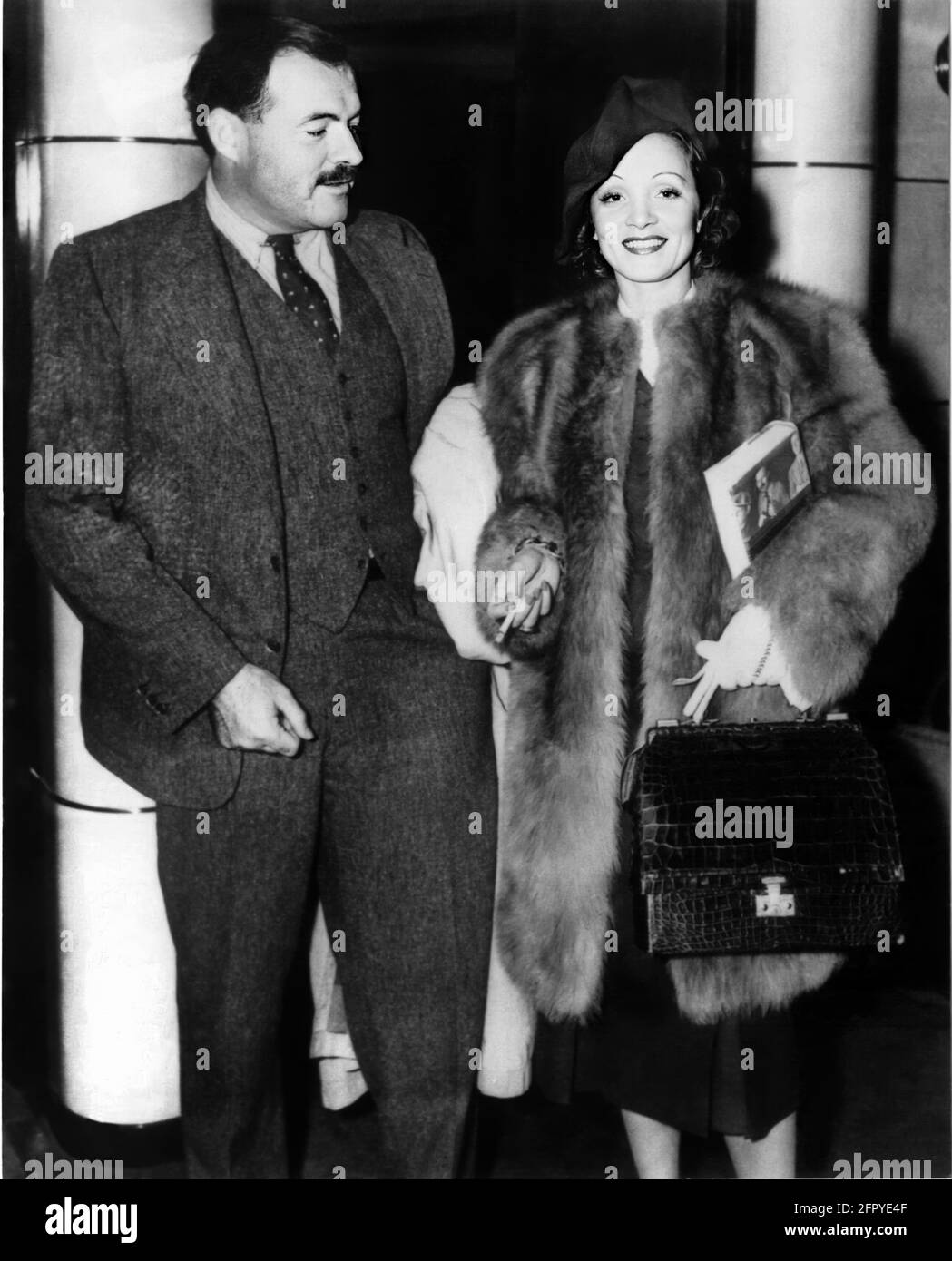 1937 , USA : der Filmstar MARLENE DIETRICH ( 1901 - 1992 ) , zur Zeit des FILMENGELS ( Angelo ) von Ernst Lubitsch , mit dem amerikanischen gefeierten Schriftsteller ERNEST HEMINGWAY ( 1899 - 1961 ). Dietrich hält eine Kopie eines Hemingway-Buches ' zu haben und nicht haben '( Avere e non avere ) von pubblisher Scribner's . Dieses Buch wurde 1944 (ACQUE DEL Sud) mit Humphrey Bogart und Lauren Bacall für den Film adaptiert. Der von Howard Hawks inszenierte Film veränderte den Schauplatz der Geschichte von Key West zu Martinique.das Drehbuch, das den Roman mit großer Freiheit neu interpretiert, wurde von Jules Furthman und Nobel la gebaut Stockfoto