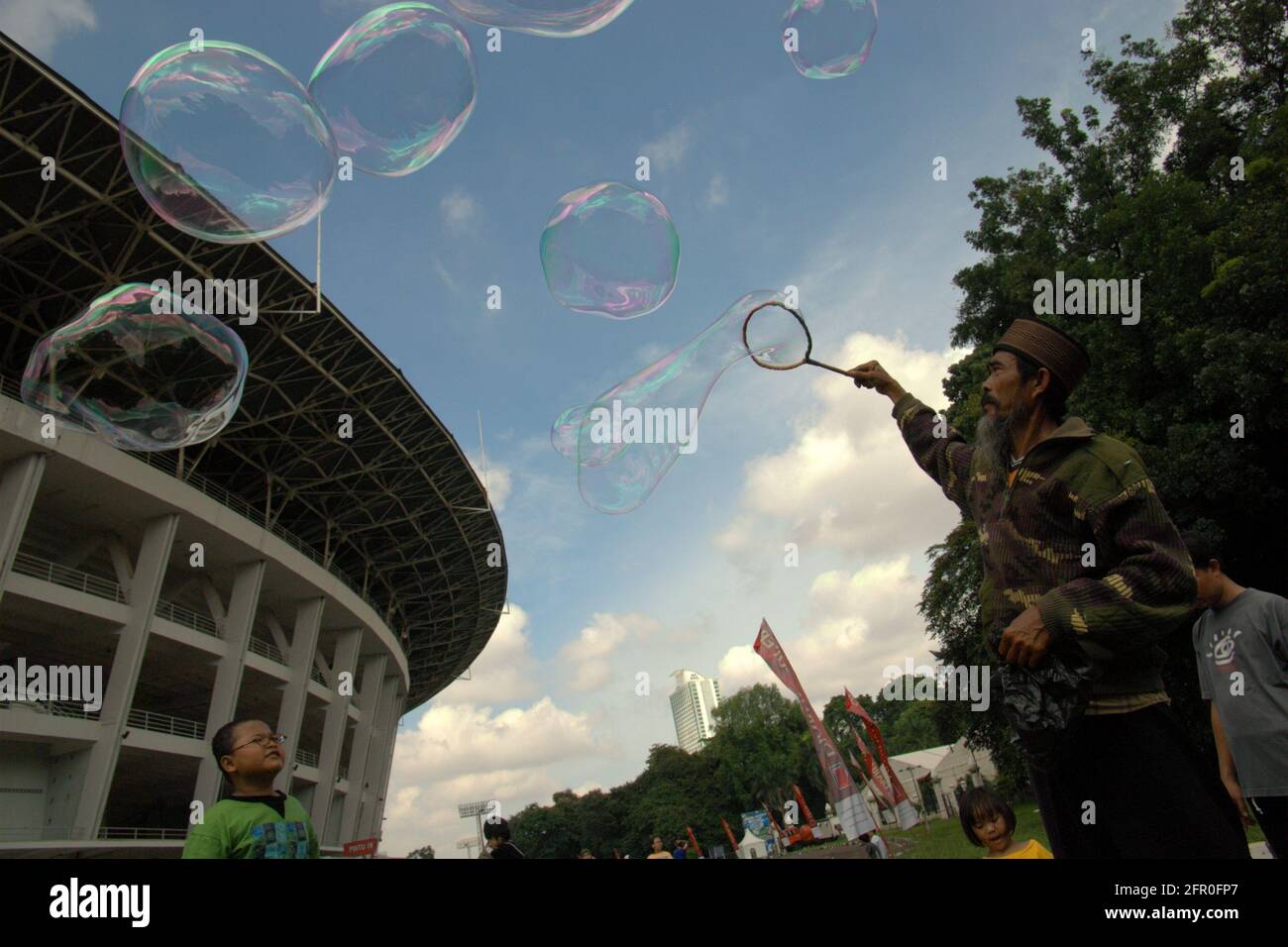 Eine Seifenblase unterwegs Seifenblasen mit Kindern vor dem Hauptstadion im Senayan Sports Complex (Gelora Bung Karno) in Jakarta, Indonesien. Stockfoto