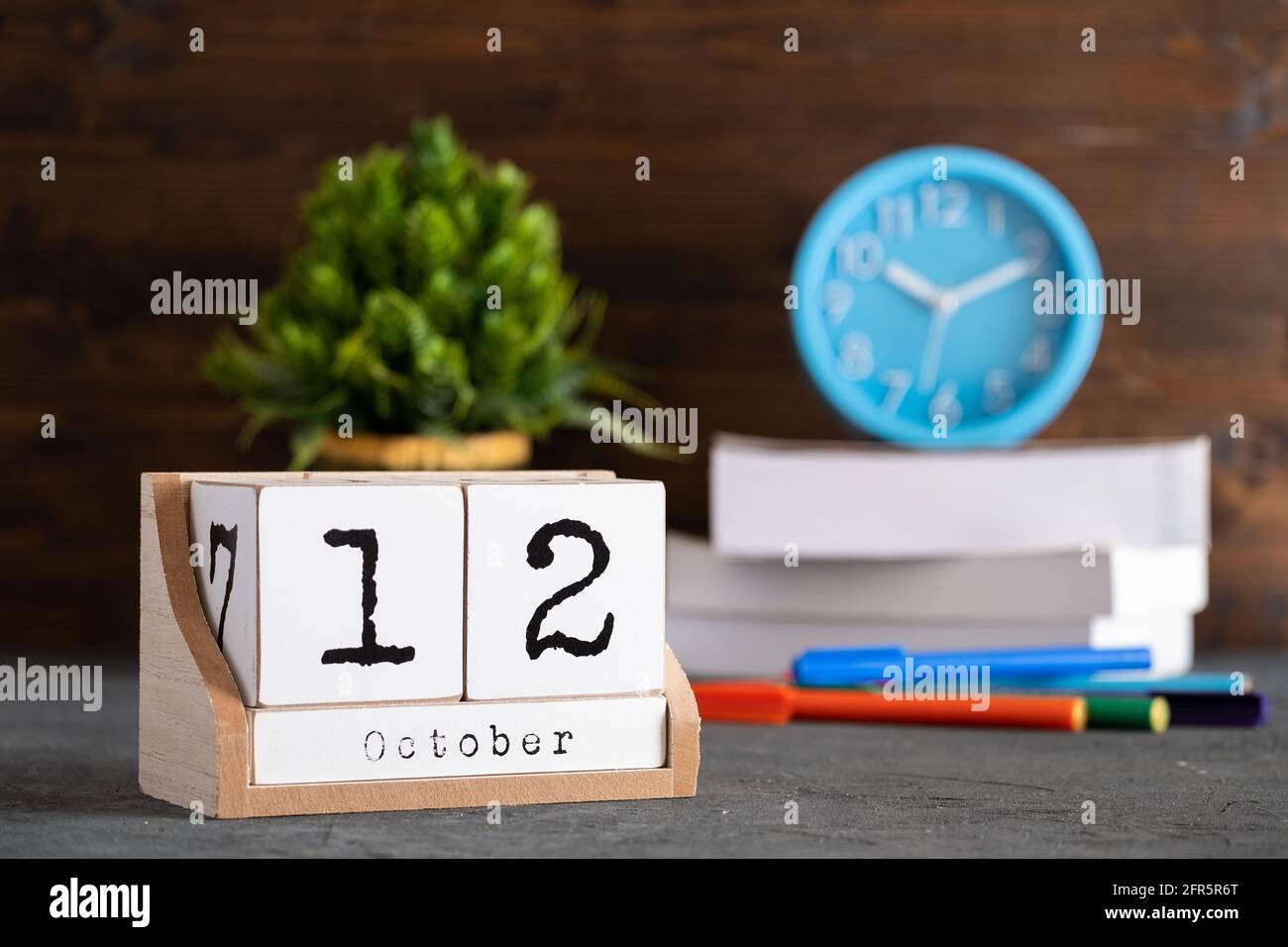 Oktober. Oktober 12 Holzwürfelkalender mit unscharfen Objekten auf dem Hintergrund. Stockfoto