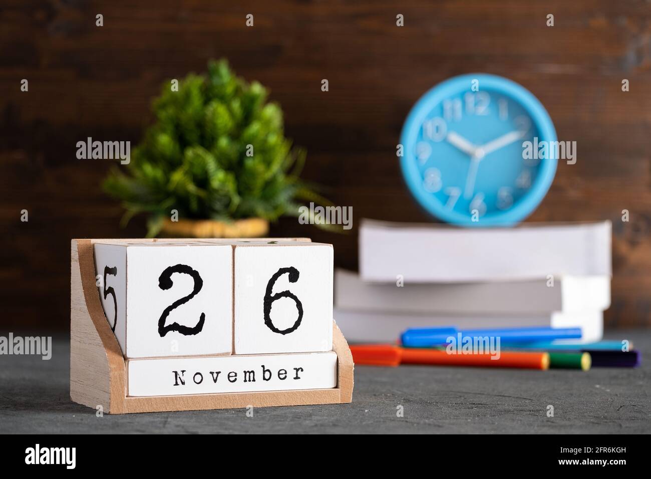 November. November 26 Holzwürfelkalender mit unscharfen Objekten auf dem Hintergrund. Stockfoto