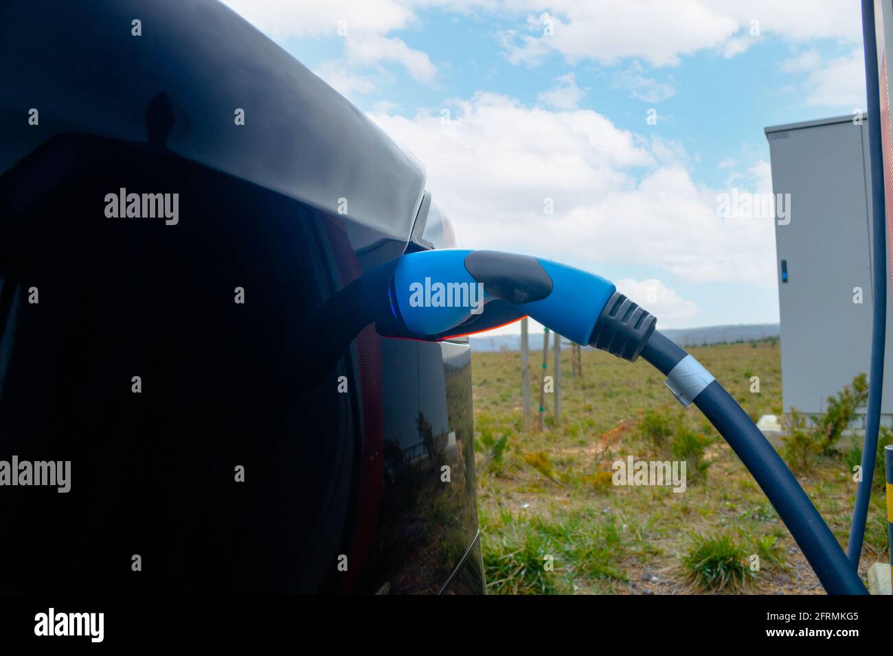 Das schnelle EV-Ladegerät wird an das schwarze EV-Fahrzeug im Fokus angeschlossen. Hochwertige Fotos. Kfz-Ladekabel für Elektroautos. Technologie der Zukunft. Emissionsfreies Fahrzeug. Kohlenstofffrei. Stockfoto