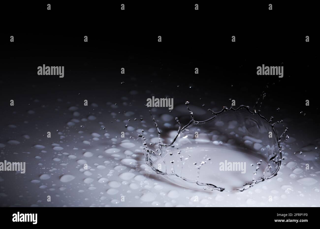 Splash Krone aus einem Tropfen Wasser fallen auf eine harte Oberfläche. Auf schwarzem Hintergrund Stockfoto