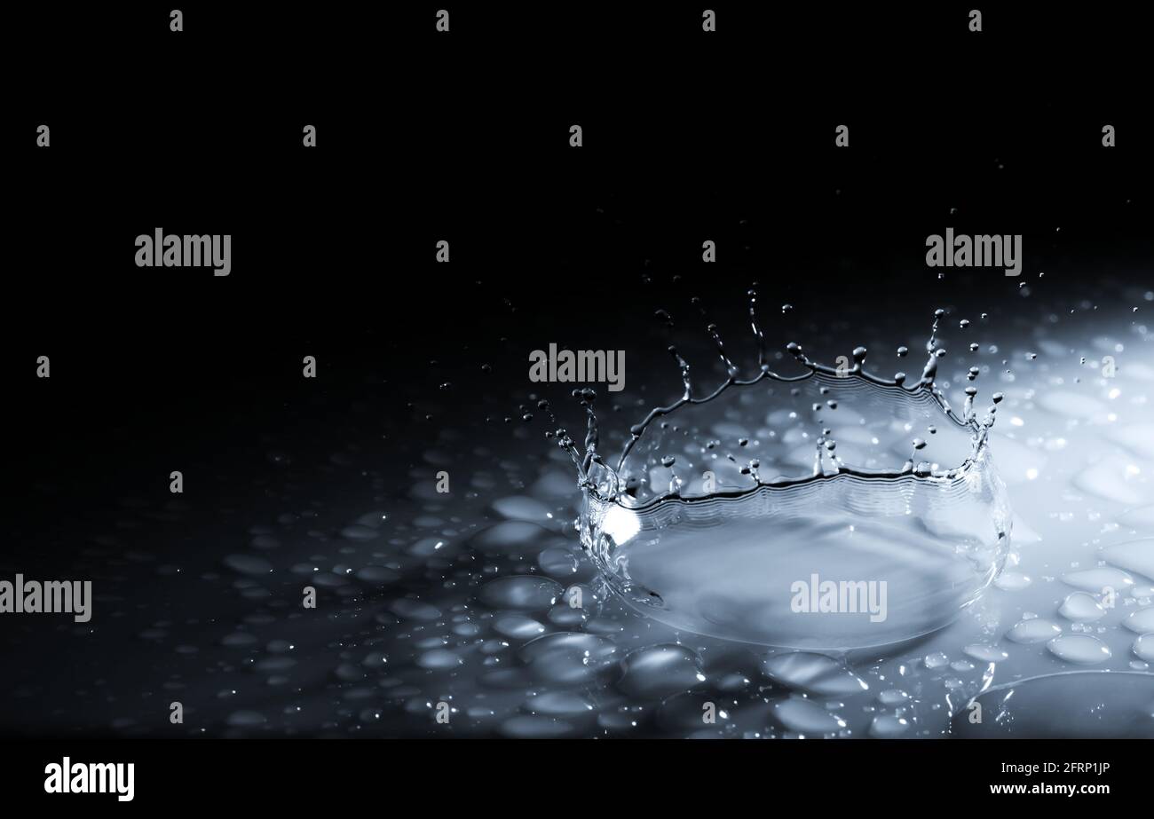 Splash Krone aus einem Tropfen Wasser fallen auf eine harte Oberfläche. Auf schwarzem Hintergrund Stockfoto