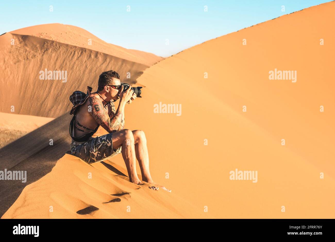 Einsamer Mann Fotograf sitzt auf Sand in Dune 45 in Sossusvlei - Konzept der Fernweh in der namibischen berühmten Wüste - Abenteuer Reise Stockfoto