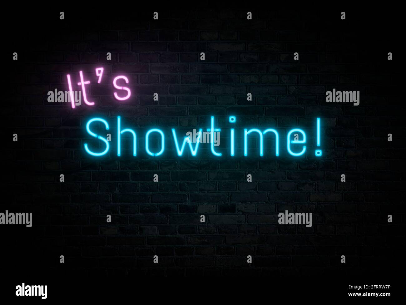 Leuchtendes und leuchtendes Pink und Blau „IT's Showtime!“ Neonschild an der dunklen Ziegelwand. Stockfoto
