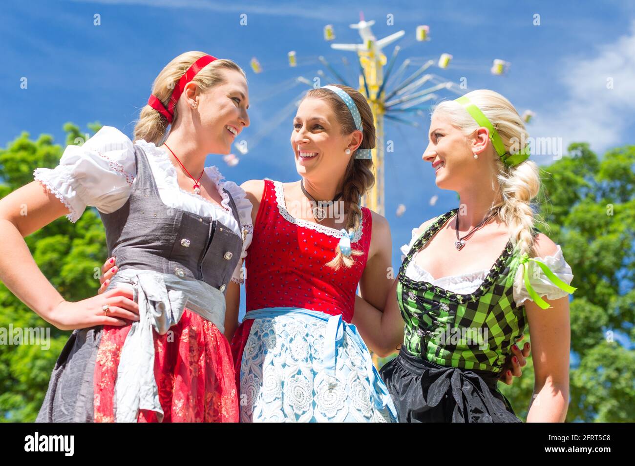 Frauen Freunde besuchen bayerischen Volksfest im Dirndl stehen vor Karussell Stockfoto