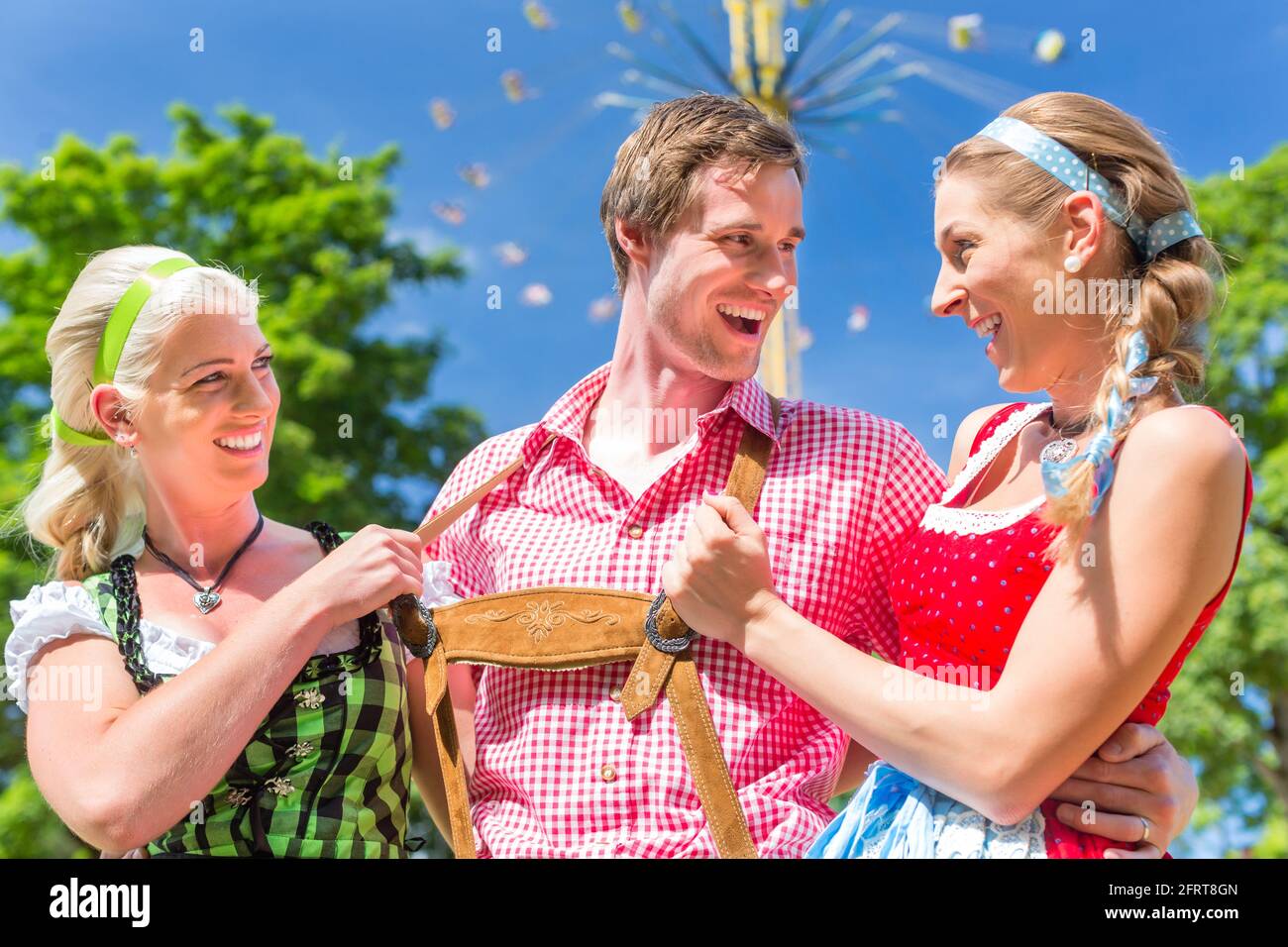 Frauen Freunde besuchen bayerischen Volksfest im Dirndl stehen vor Karussell Stockfoto