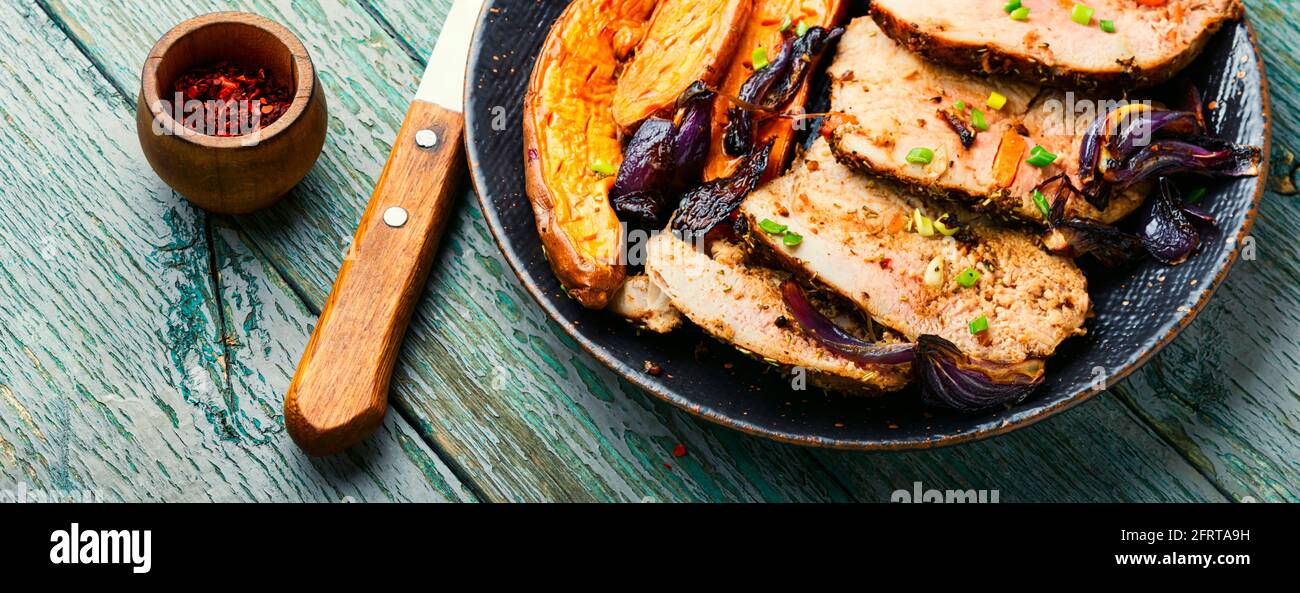 Scheiben gebackenes Fleisch mit Süßkartoffeln.Gebratenes Schweinefleisch mit Gemüsegarnitur auf Holztisch Stockfoto