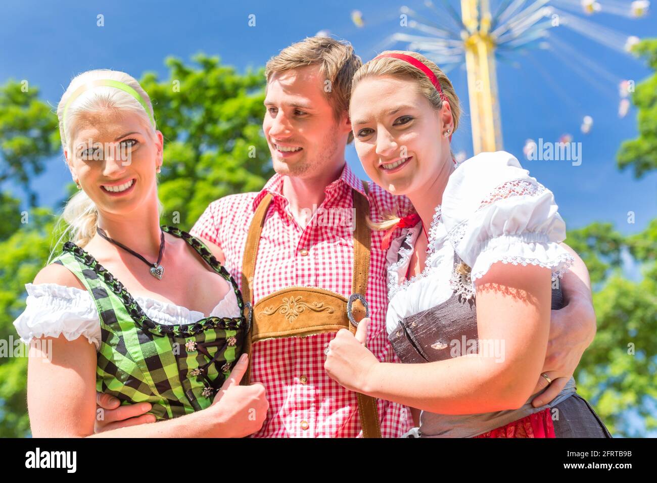 Frauen Freunde besuchen bayerischen Volksfest im Dirndl stehen vor Karussell Stockfoto