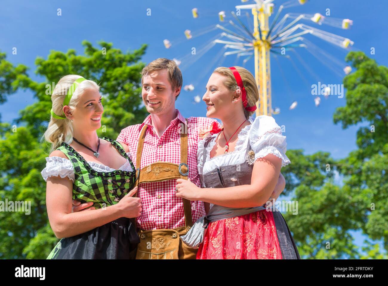 Frauen Freunde besuchen bayerischen Volksfest im Dirndl stehen vor Karussell Stockfoto