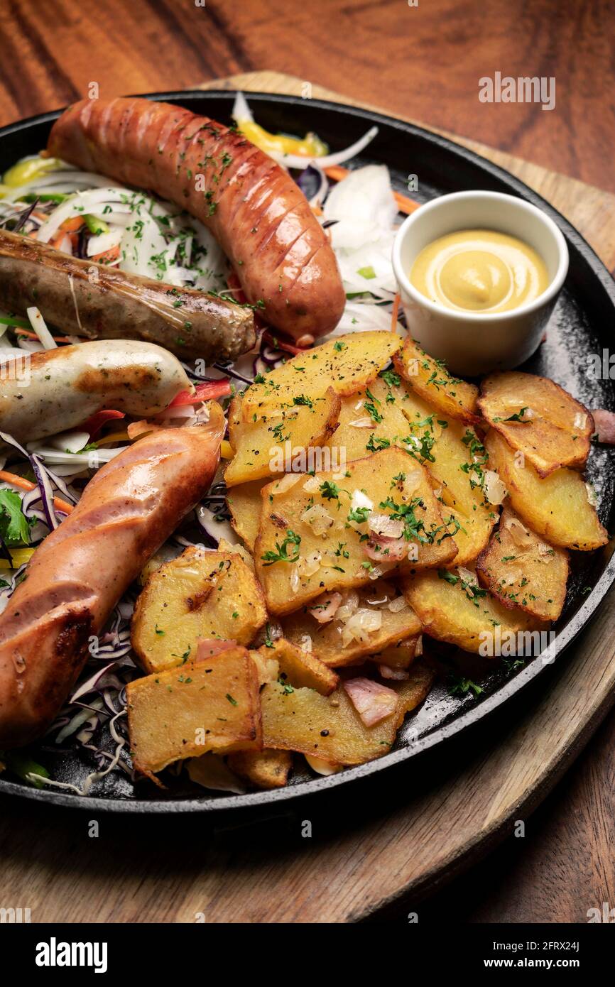 Gemischte deutsche traditionelle Bio-Wurst- und Kartoffelmahlplatte mit Nurenberger, Lamm und Schweinefleisch mit Salat und Senf Stockfoto