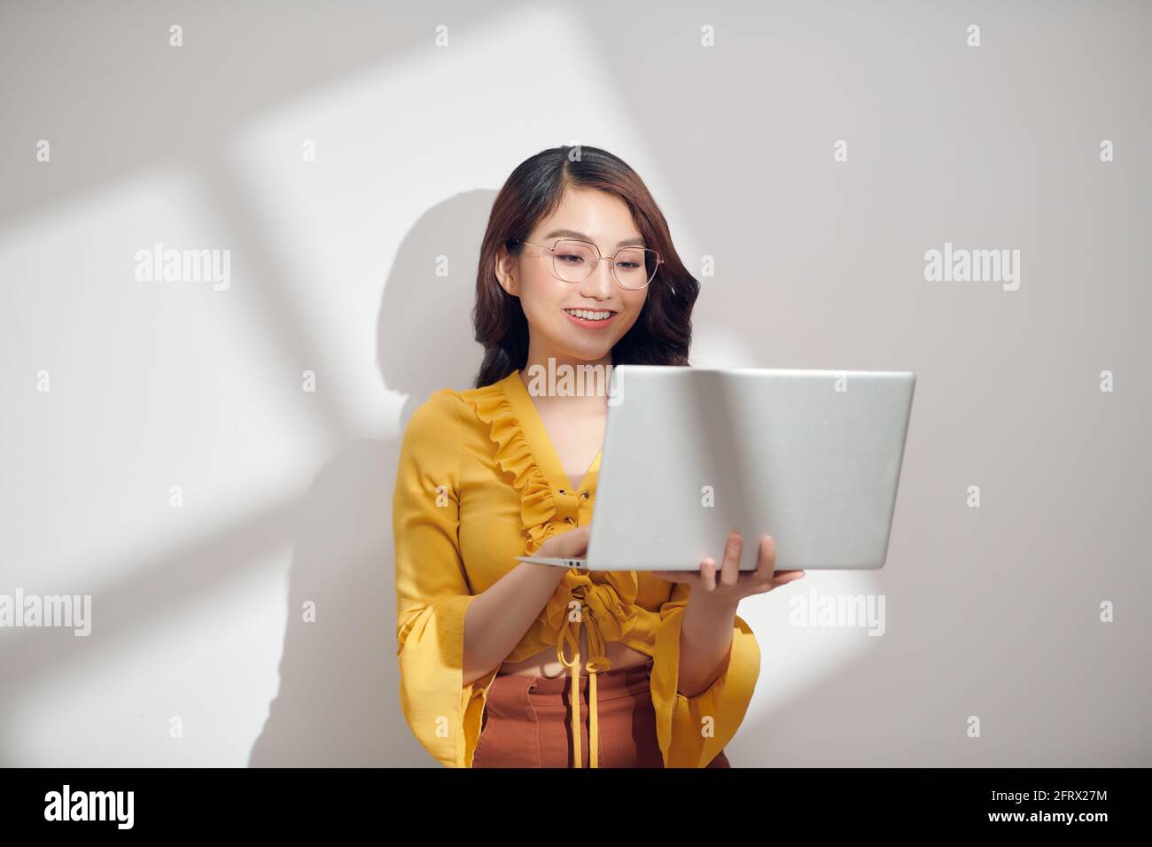 Porträt einer glücklichen asiatischen Geschäftsfrau hält Laptop-Computer und Blick weg soliert über weißen Hintergrund Stockfoto