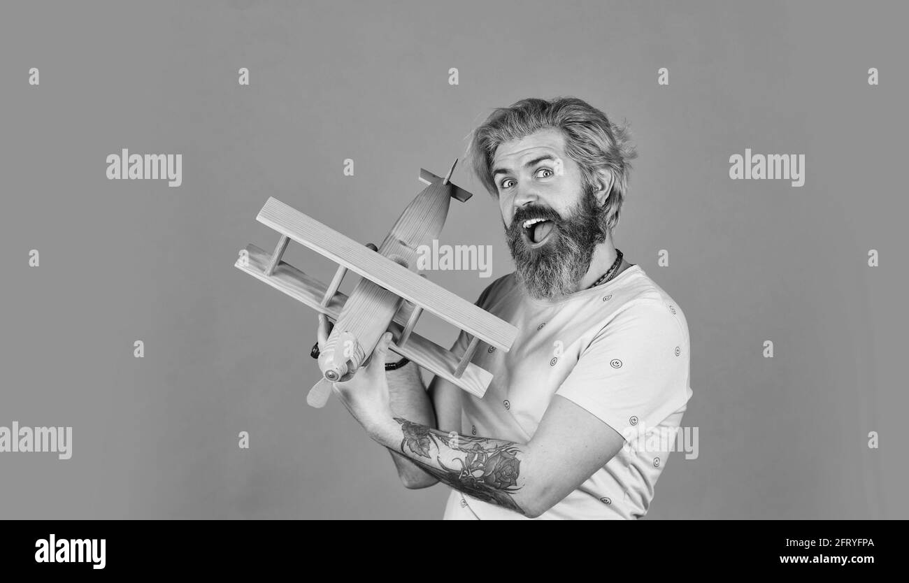 Das ist erst der Anfang. Flugreisen. Transportkonzept. Kindheitstraum. Aviator bärtiger Hipster-Mann. Spielzeug aus einem hölzernen Flugzeug. Fliegen Sie mit dem Flugzeug. Buchen Stockfoto