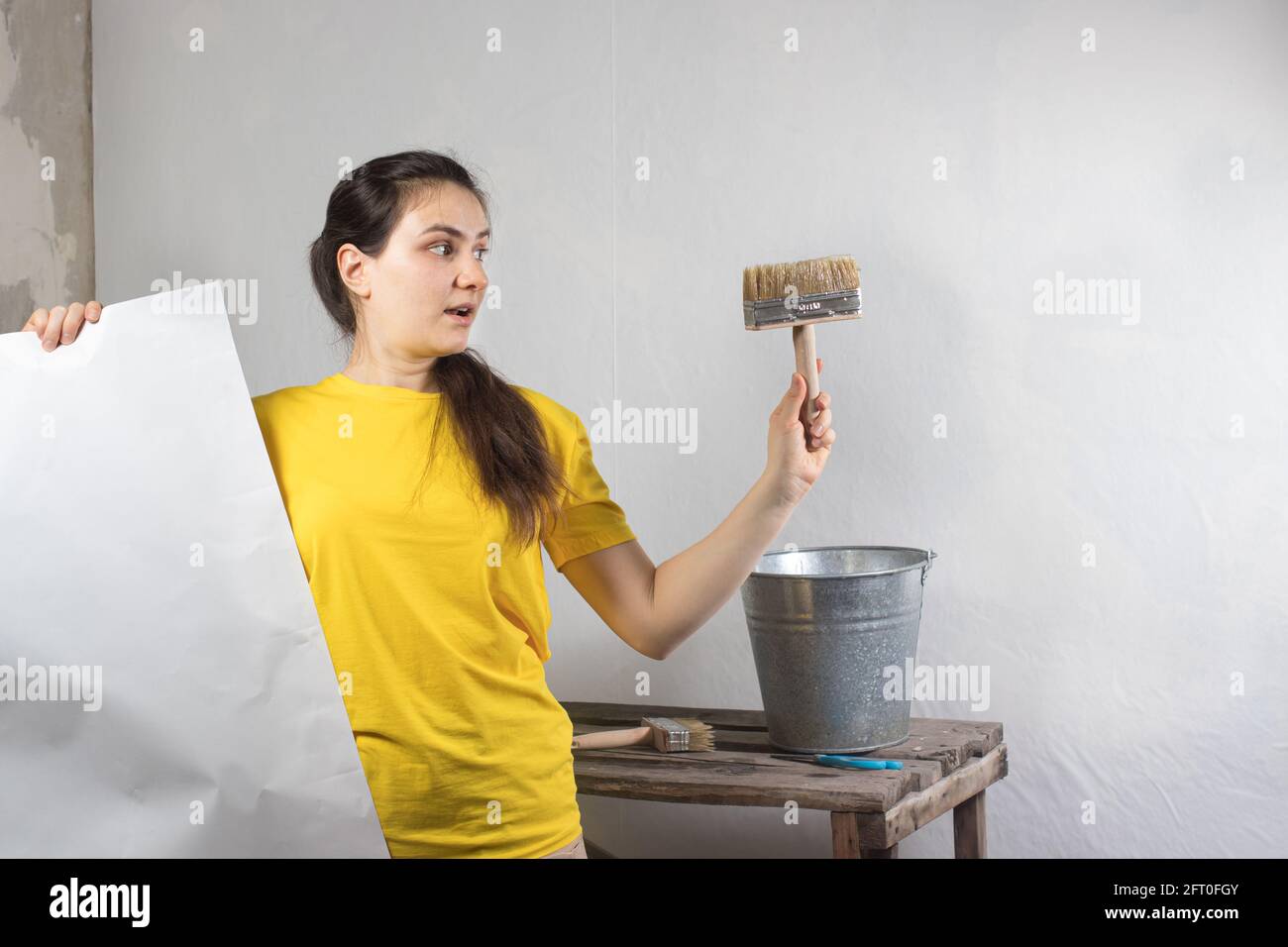 Eine Reparaturfrau klebt weiße Tapeten an die Wand. Reparaturarbeiten, Tapezieren. Platz für Textkopie. Stockfoto