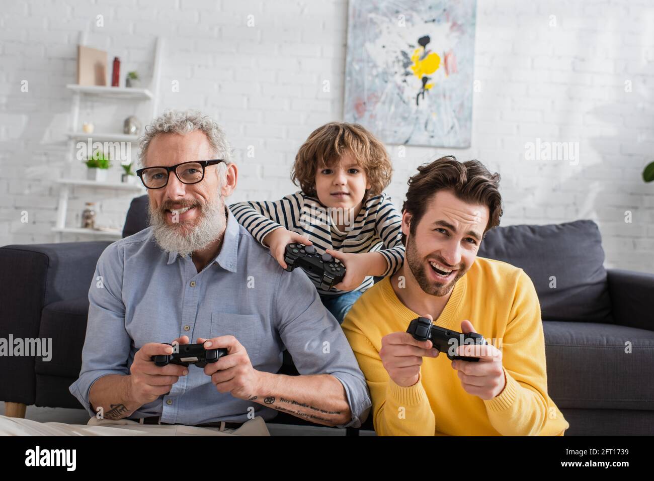 KIEW, UKRAINE - 12. APRIL 2021: Lächelnde Männer und Jungen mit Joysticks zu Hause Stockfoto