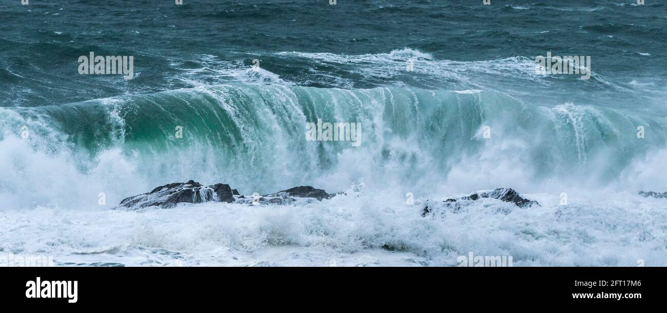 Ein Panoramabild einer wilden Welle, die auf den Cribbar Rocks an der Küste von Newquay in Cornwall bricht. Stockfoto