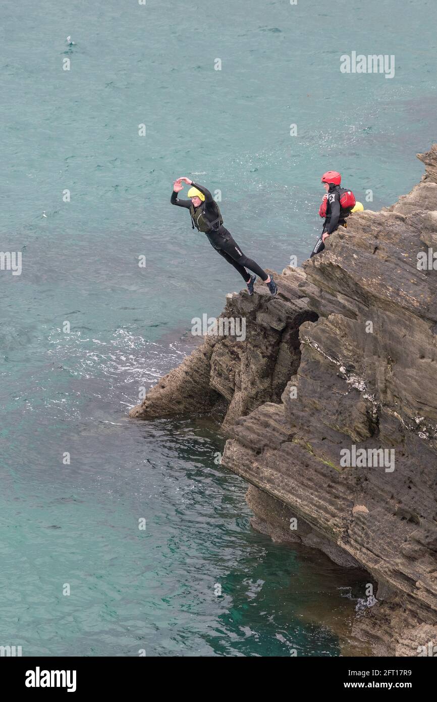 Ein Urlauber, der während einer Sitzung rund um die Gezeitenzone in Towan Head in Newquay in Cornwall von den Felsen springt. Stockfoto