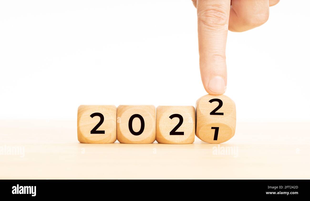 Handwechselnde Holzblöcke mit der Nummer 2021 bis 2022. Konzept für das neue Jahr. Speicherplatz kopieren. Weißer Hintergrund Stockfoto