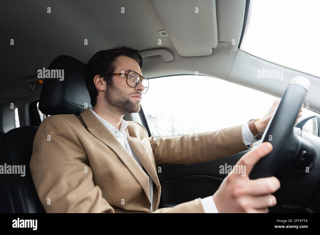 Bärtiger Mann mit Brille fährt modernes Auto Stockfoto