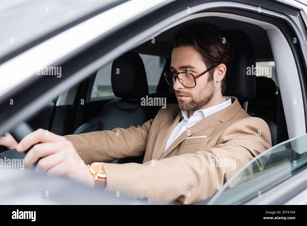 Bärtiger Mann mit Brille fährt modernes Auto Stockfoto