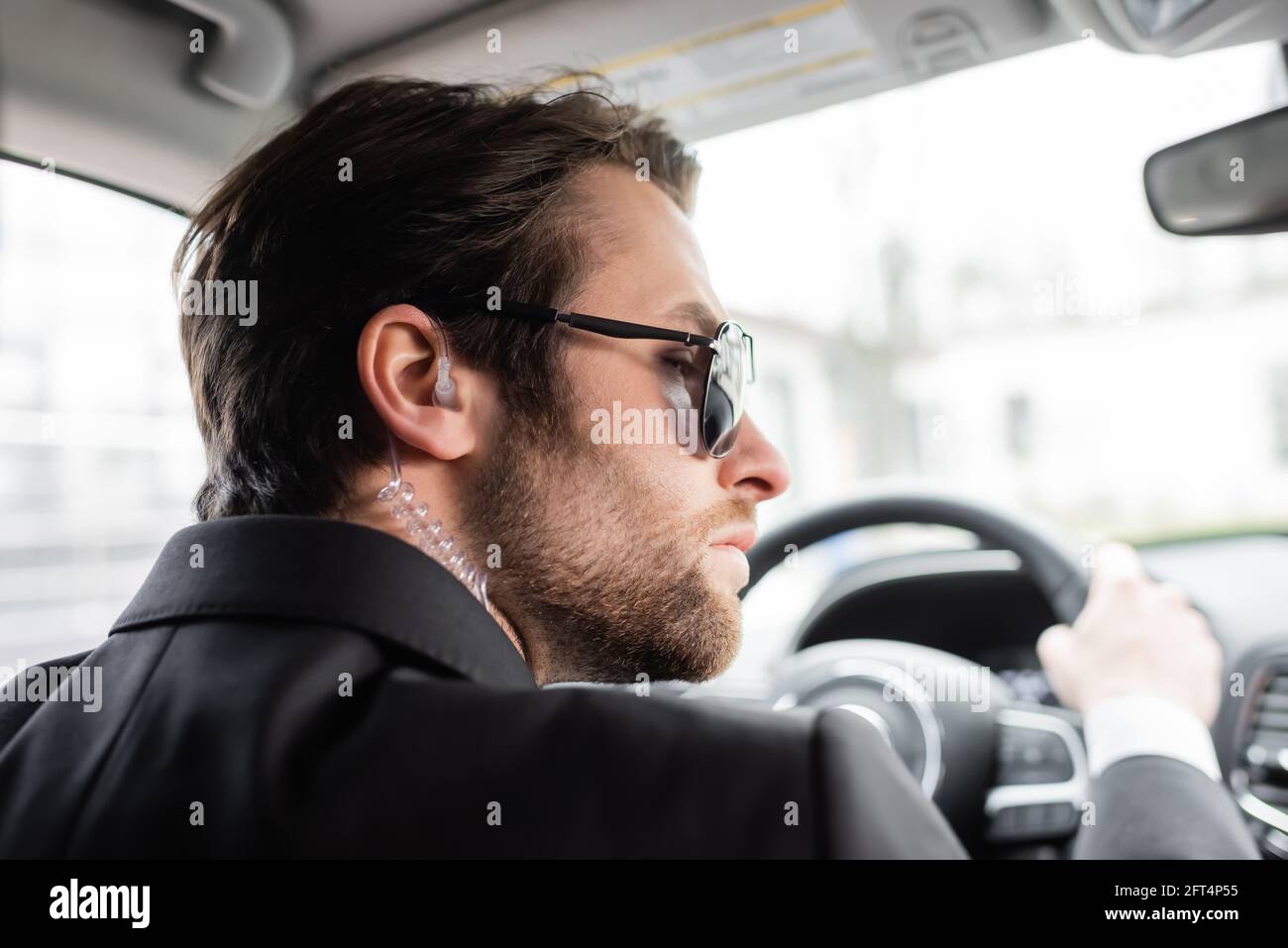 Bärtiger Bodyguard in Sonnenbrillen, der moderne Automobile fährt Stockfoto