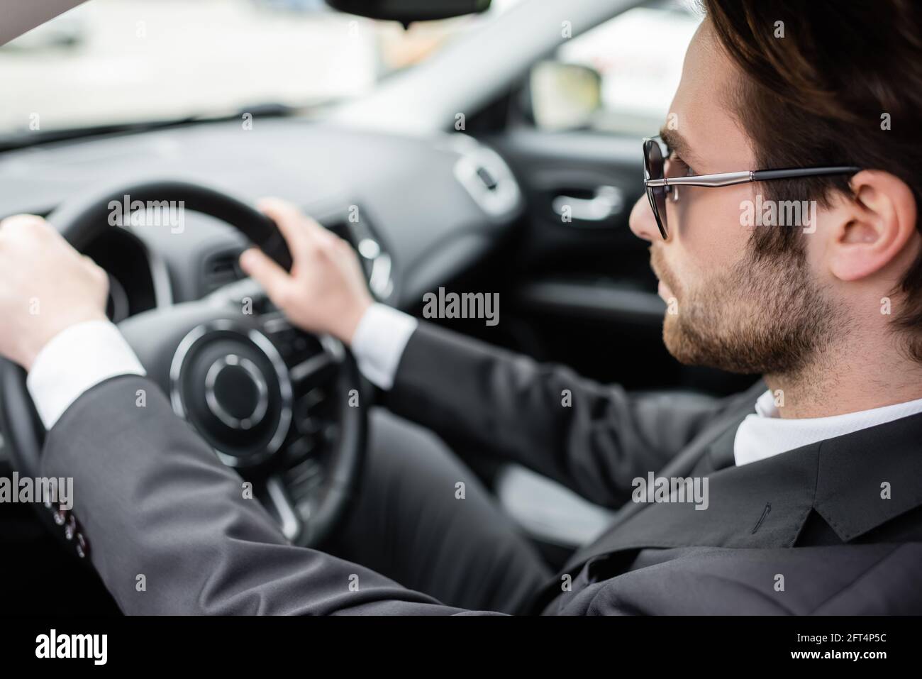 Bärtiger Mann mit Sonnenbrille, der ein modernes Automobil fährt Stockfoto