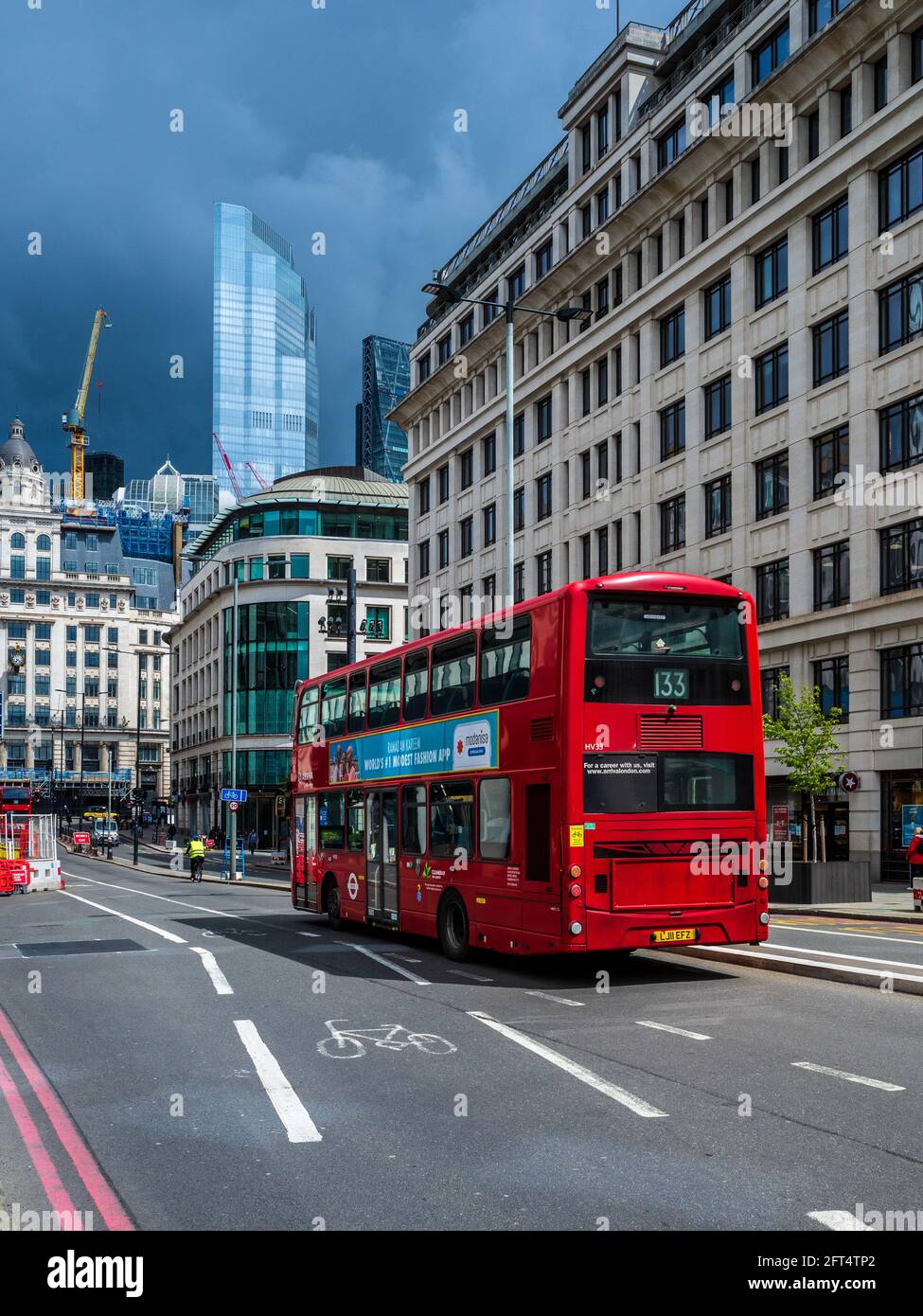 Stürmischer Himmel über dem Finanzdistrikt der City of London. Ein roter Londoner Bus im Finanzdistrikt der City of London. Stockfoto