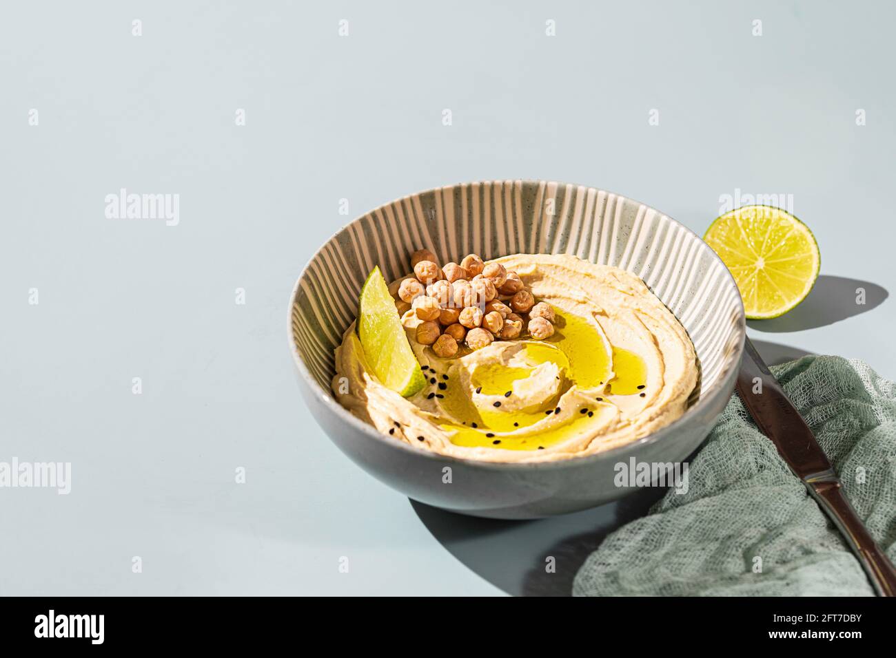 Kichererbsen-Hummus mit Olivenöl und Kalk auf einer Keramikplatte. Hausgemachter klassischer Hummus. Kichererbsen-Gerichte, vegetarisches Gericht. Selektiver Fokus, Kopierbereich. Stockfoto