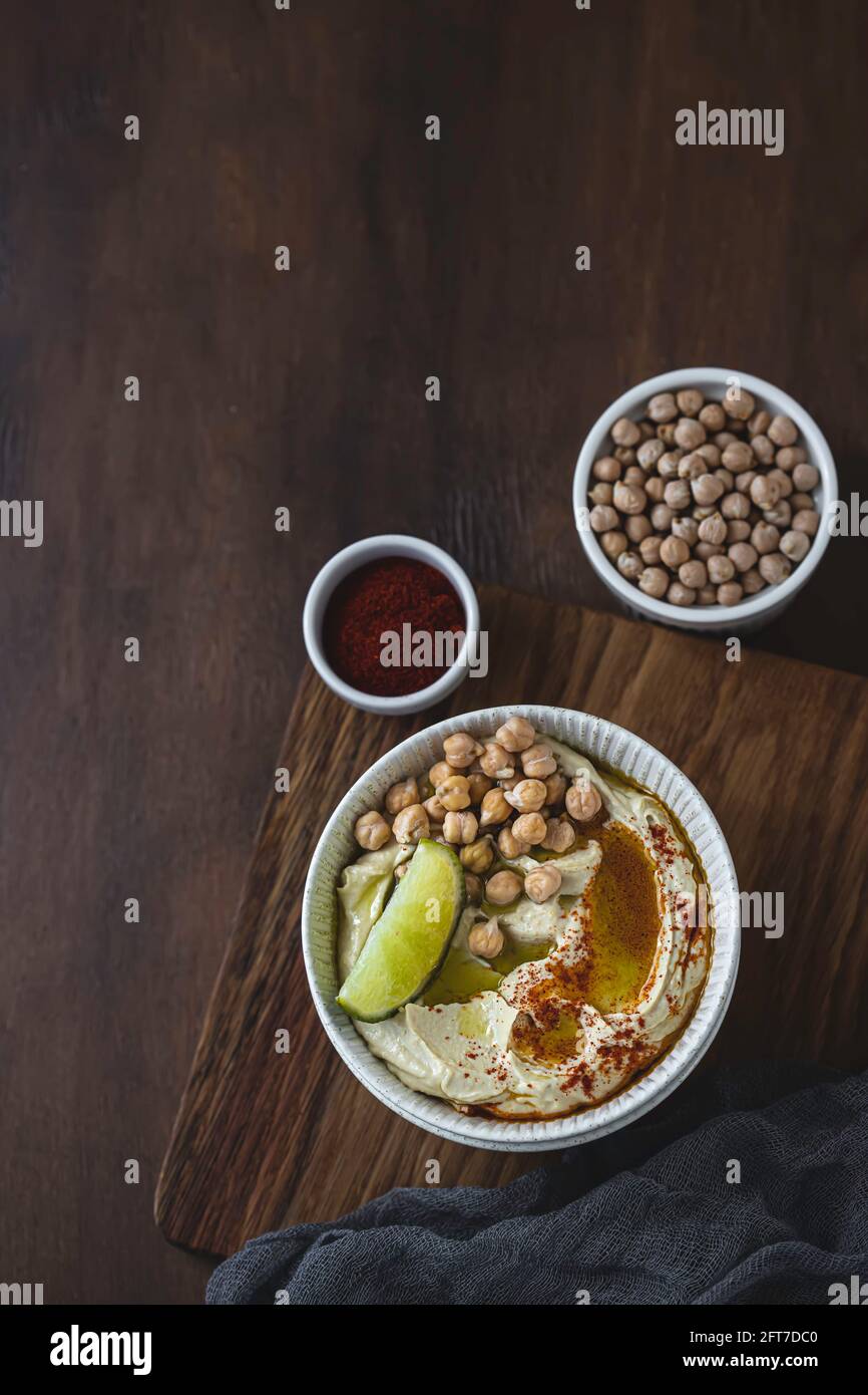 Kichererbsen-Hummus mit Olivenöl und Kalk auf einer Keramikplatte. Hausgemachter klassischer Hummus. Kichererbsen-Gerichte, vegetarisches Gericht. Selektiver Fokus, Kopierbereich. Stockfoto