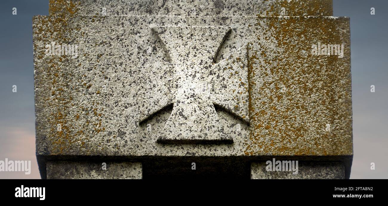 Verwittertes Kriegskreuz auf einem Denkmal aus Granit in Erinnerung an die Toten der beiden Weltkriege in Deutschland Stockfoto