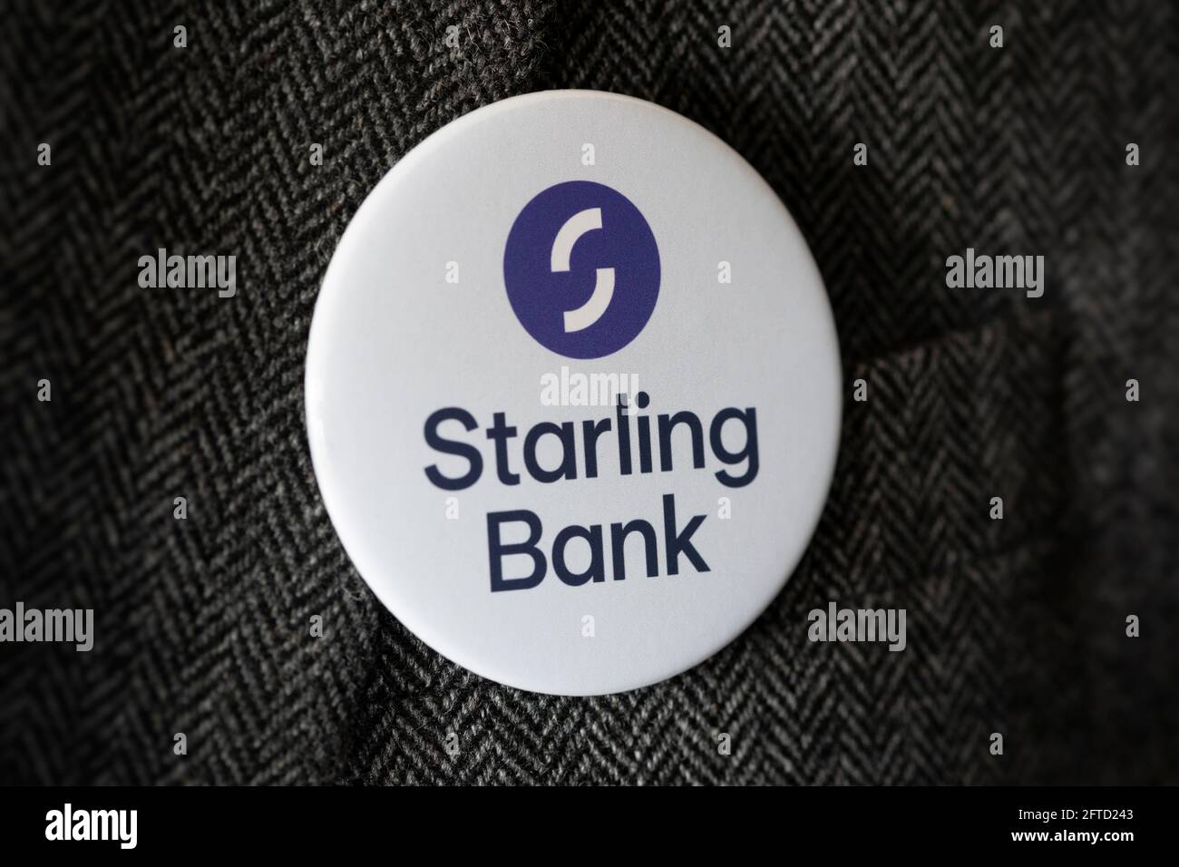 Ein Knopfabzeichen mit dem Logo der Starling Bank, das an einer Jacke befestigt ist. Stockfoto