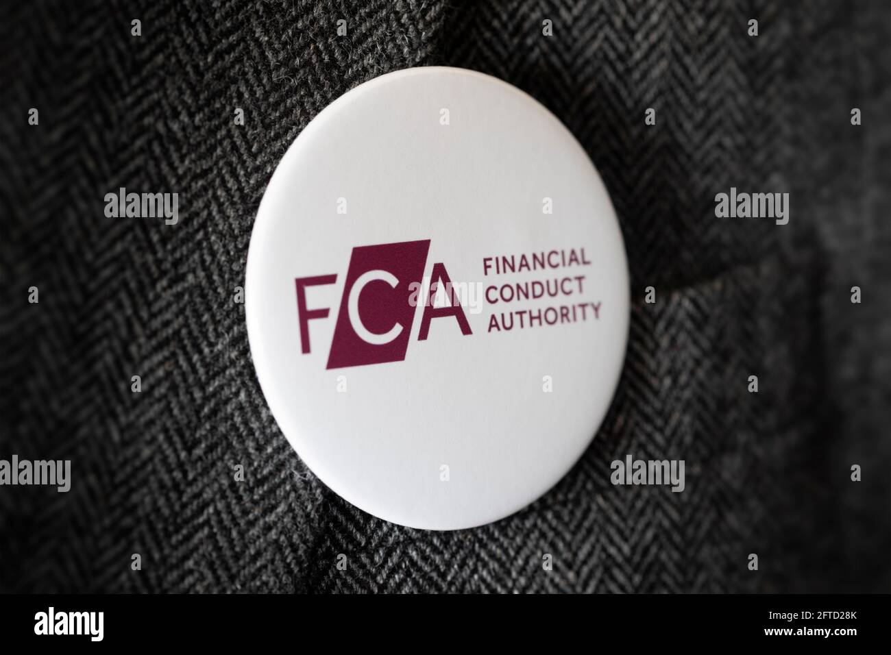Ein Knopfabzeichen mit dem Logo der FCA Financial Conduct Authority, das an einer Jacke befestigt ist. Stockfoto